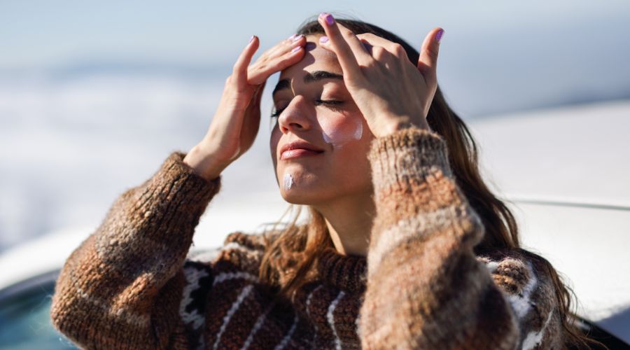 girl putting on sunscreen to protect skin from damage and aging